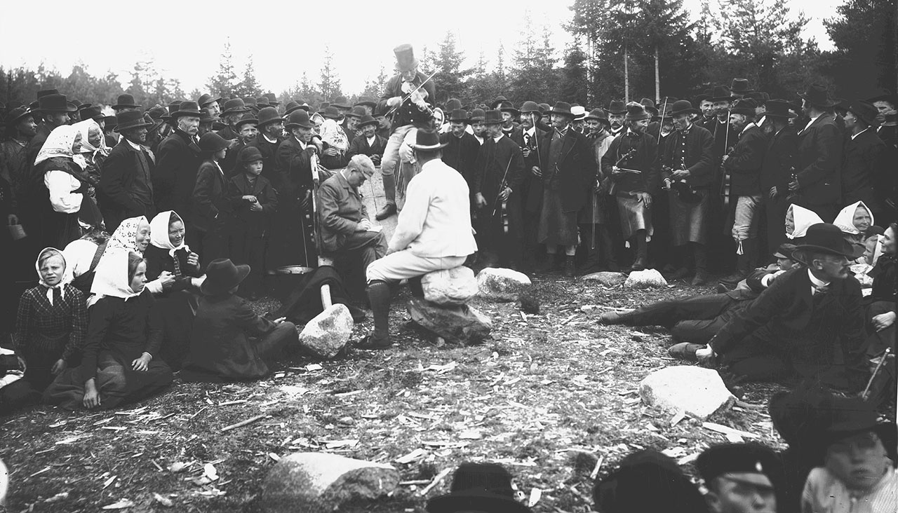 Spelmanstävlingen vid Gesunda 1906. På bilden sittande vid kärran Nils Andersson och Anders Zorn. På kärran Troskari Erik Persson, Malung. Foto: Gerda Söderlund. Leksands kulturhistoriska arkiv.